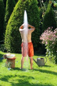 Mann unter der Gartendusche