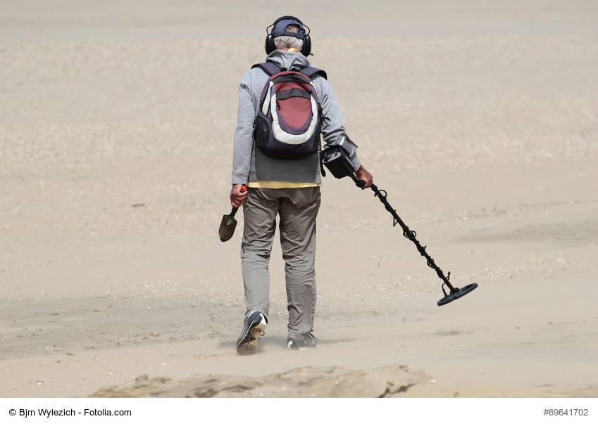Mann mit Metalldetektor am Strand